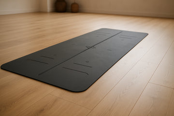 A high-quality non-slip yoga mat with clear alignment lines laid out in a yoga studio. Alt: Non-slip yoga mat with alignment lines for posture and grip.